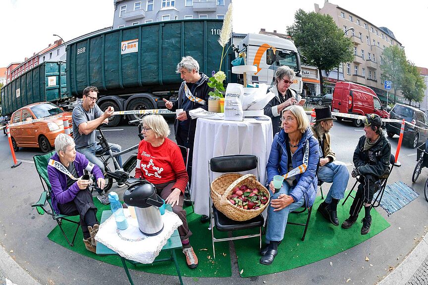 Park(ing) Day 2019 in Berlin-Tempelhof Auf dem Parking Day 2019 in Berlin-Tempelhof haben Menschen einen Tisch mit Kaffee und Obst aufgestellt und unterhalten sich in entspannter Atmosphäre.